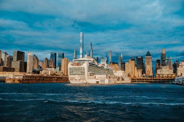 Alacakaranlıkta Manhattan 'da gemi turu. Manhattan Limanı 'nda büyük bir yolcu gemisi var. Arkasında şehrin gökdelenleri var..