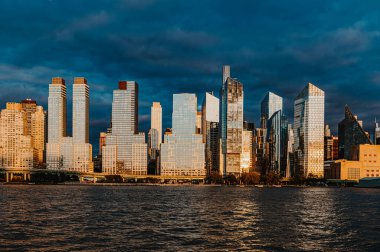 Gün batımında Manhattan silueti. Gökdelenler nehri yansıtırken günbatımı Manhattan 'ın renkleri nefes kesici bir manzara yaratıyor..