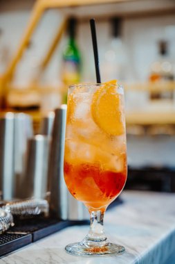 Portakal dilimli taze bir kokteyl. Üzerinde portakal dilimi olan renkli bir kokteyl mermer tezgahta duruyor, canlı katmanlar ve kabarcıklar sergiliyor..