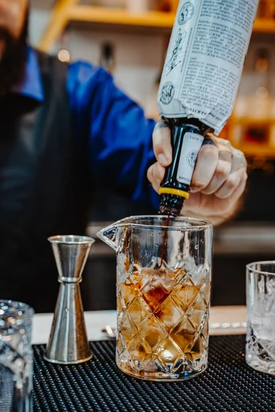 Denver, ABD, 14 Ağustos 2024: Barmen bir barda kokteyl hazırlıyor. Uzman barmen, barda canlı bir akşam kokteyli hazırlarken bardağa malzemeler doldurur..