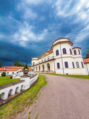 Doğada dramatik bir gökyüzüne karşı tarihi bir yapı. Bulutlu bir gökyüzü ve yeşillik tarafından çerçevelenmiş büyük tarihi bir bina çarpıcı mimari detaylarını vurguluyor..
