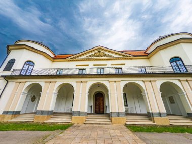 Bulutlu bir gökyüzünün altında kemerleri olan tarihi bir bina. Büyük tarihi bir yapıda zarif kemerler ve gün boyunca dramatik bulutlu bir gökyüzü altında ayrıntılı bir cephe bulunur..