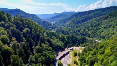 Dolambaçlı nehir ve trenle manzaralı dağ manzarası. Trenler, güneşli bir günde, kıvrımlı nehirler ve açık mavi gökyüzüyle çevrili yemyeşil dağlardan geçer..