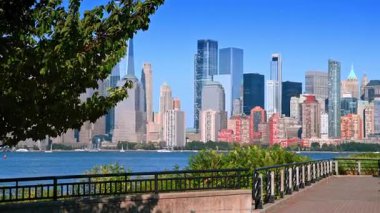 Jersey City 'deki bir parktan Manhattan ufuk çizgisi manzarası. Jersey 'de ağaçlar ve nehir kenarı geçidi Hudson Nehri' nin karşısındaki Manhattan siluetinin geniş bir manzarasına açıktır..