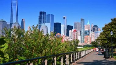 Jersey City, ABD, 16 Temmuz 2025: Jersey City 'de yeşillik çerçeveli Manhattan silueti. Jersey City 'de yeşil ağaçlar yol boyunca uzanır. Hudson Nehri boyunca yükselen Manhattan silueti....