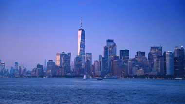 Bir Dünya Ticaret Merkezi ile Manhattan 'da gökyüzü. Manhattan silueti akşam ışığında parlıyor. Tek Dünya Ticaret Merkezi ve Hudson Nehri 'ndeki teknelerle..