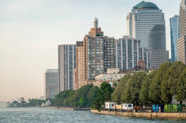 Gün batımında New York 'ta nehir kenarındaki binalar. New York 'taki konut ve ofis binaları gün batımının altında nehir kenarında duruyor..