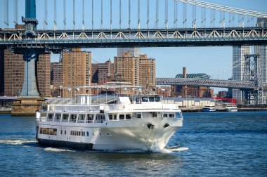 Manhattan Köprüsü 'nden geçen yolcu feribotu. Bir yolcu feribotu, arkasında Manhattan Köprüsü olan nehir boyunca yol alır..
