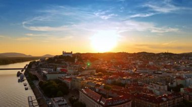 Bratislava Kalesi eski kasaba panoramasının üstünde. Beyaz Bratislava Şatosu, arka planda tepeler olan eski kasabanın çatılarının üzerinde duruyor..
