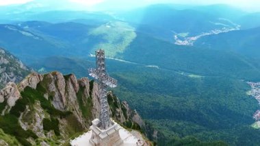 Büyük haç heykeli muhteşem kayalık arazinin üzerinde yükseliyor. Romanya 'daki Caraiman Dağı' ndaki Kahramanlar Haçı üzerindeki İHA görüntüleri.