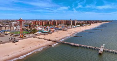 Brooklyn, New York, ABD 'deki Coney Island sahilindeki uzun iskeleye yaklaşıyoruz. Kumsallara ve lunaparka bakın..