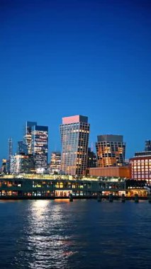 Günbatımında New York 'un parlak, modern silueti. Şehir turu için nehir kıyısında bir nehir gezisi. Dikey video.