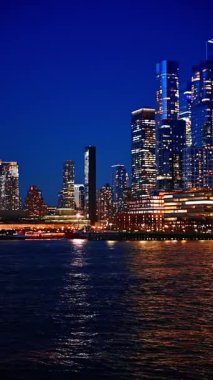 Alacakaranlıkta göz kamaştırıcı güzel New York 'u gezmek. Nehir teknesinden şehir manzarasını izliyor ve hayranlık duyuyorum. Dikey video.