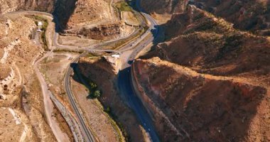 Kanyonlar arasındaki dalgalı otoyollara arabalar ve kamyonlar biniyor. Güneşli bir günde ABD 'nin Utah eyaletindeki Price Canyon üzerinde insansız hava aracı görüntüleri..