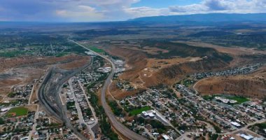Dağlık bölgedeki kentsel alanın üzerinde uçuyorlar. Manzarayı geçen otobanın üzerindeki görüntüler. Utah, ABD.
