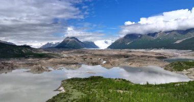 Amerika, Alaska 'nın çarpıcı doğal manzarası. Nehrin üzerinde yükselen drone, bulutlarla kaplı muhteşem kar kaplı kayaları gözler önüne seriyor..