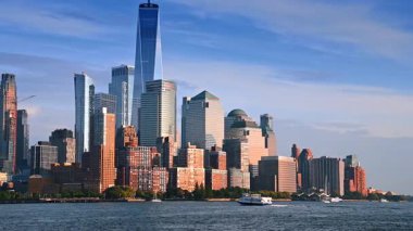 Bir nehir botu Doğu Nehri 'nin rıhtımına doğru gidiyor. Günbatımında New York, ABD 'nin modern ufuk çizgisinin alçak açılı görüntüsü.