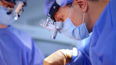 Cerrah beyin ameliyatına cerrahi lenslerle odaklanmıştı. Büyüteç takan bir tıp uzmanı beyin cerrahisi yapıyor. Doktor hassas bir ameliyata odaklanmış durumda..