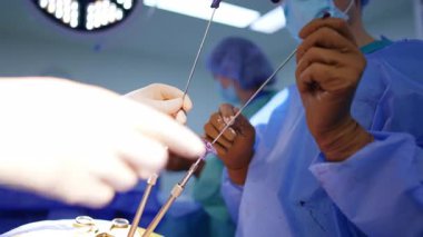 Beyin cerrahisinde cerrahi aletleri olan cerrahların elleri. Hassas ameliyatlar sırasında cerrahi aletler tutan tıbbi uzmanlara yakın durun. Prosedür hassasiyeti ve takım çalışmasını gösteriyor..