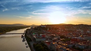 Slovakya 'nın Bratislava şehrinde altın saat. Tuna 'nın su yüzeyindeki drone görüntüleri güneşin batışının yumuşak ışığını yansıtıyor..