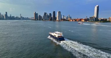 New York, ABD, 1 Ağustos 2025: Su manzarası boyunca seyahat eden bir motorlu tekneye yetişmek. Güneşli bir günde New York 'un silüeti.