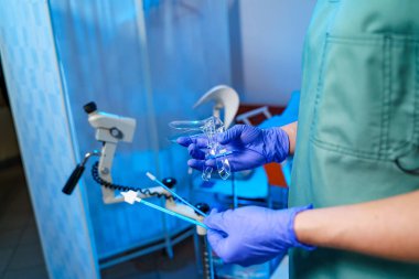 Doktor klinik muayenesi için araç gereç ayarlar. Mavi eldivenli bir tıp uzmanı, parlak bir klinikte ameliyat için gerekli aletleri bulundurur..