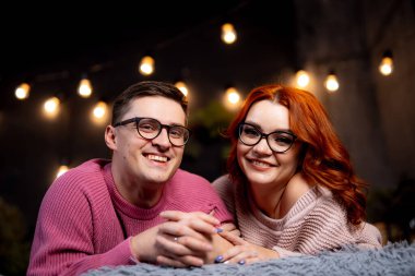 Genç çift dışarıda sıcak bir akşam geçiriyorlar. Neşeli bir çift gece dışarıda, parlayan ışıklarla çevrili olarak rahatlıyor. Gülümseyip el ele tutuşuyorlar..