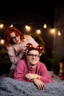 Kış dekorasyonuyla kutlama yapan bir çift. Bir kadın, erkek evinde sıcak bir kış akşamının tadını çıkarırken kafasında şenlikli süsler düzenler..