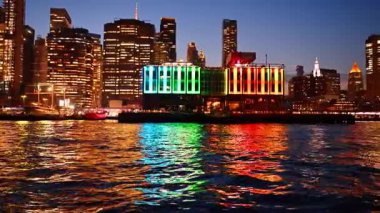 Geceleri New York 'ta suyun rengarenk yansımaları. Gökkuşağı renginde parlak bir bina New York 'ta geceleri suyu yansıtıyor..