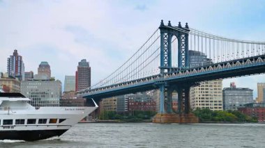 New York, ABD, 1 Ağustos 2025, feribot Manhattan Köprüsü 'nün altından geçiyor. Beyaz bir feribot Manhattan Köprüsü ve şehrin silueti ile Doğu Nehri boyunca yol alır..