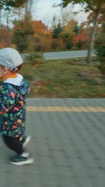 Mutlu heyecanlı erkek bebek yolda neşeyle koşar. Çocuk parktaki ahşap heykeli görünce duruyor. Dikey video