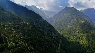 Yeşillik ormanları tarafından ağaçlandırılmış dev kayaların çene kırıcı manzarası. Romanya 'daki Karpat Dağları üzerinde dramatik bulutlar gökyüzünü kaplıyor. Hava görünümü.