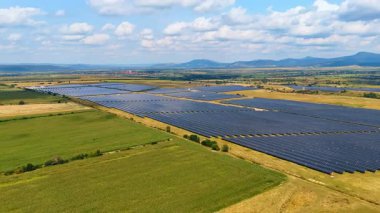 Güneş panelleri yakınlarındaki yeşil tarım alanları. Fotovoltaik panel yenilenebilir enerji üretiyor. Hava görünümü.