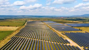 Kırsal alana yerleştirilmiş fotovoltaik paneller. Güneş ışığının enerjisinden yeşil enerji üretimi. Hava görünümü.