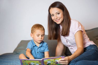 Mother and her baby boy studying chldren's book (real family). clipart