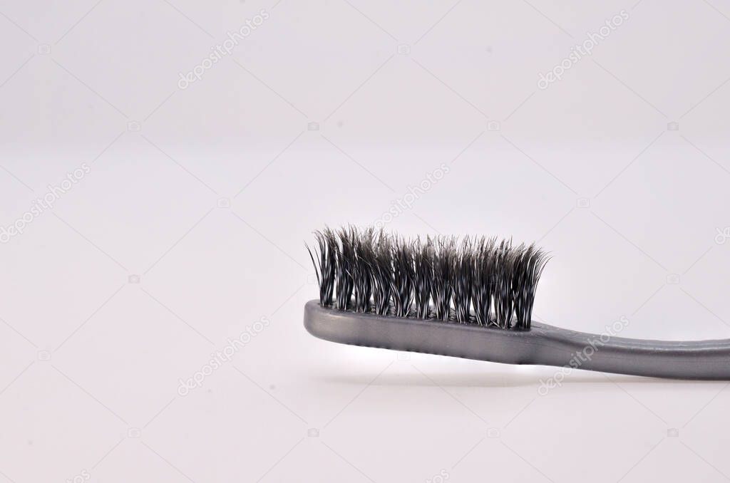 Old black toothbrush on white background