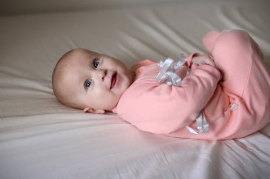 Mavi gözlü bir bebek beyaz bir çarşafın üzerinde yatıyor..