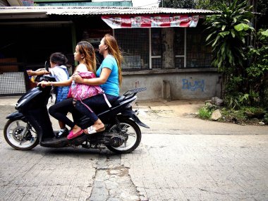 Antipolo City, Filipinler - 18 Haziran 2018: İki bayan ve küçük bir kız bir yokuş yukarı bir yol, motosikletin.