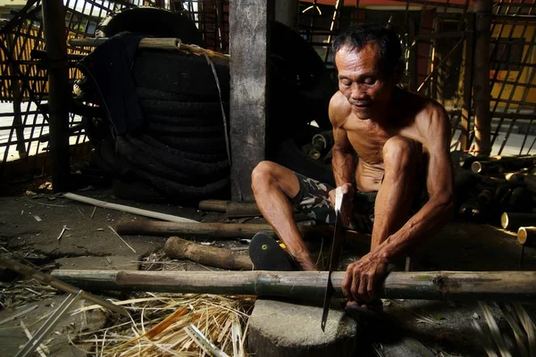 Photo of a bamboo furniture maker cutting bamboo