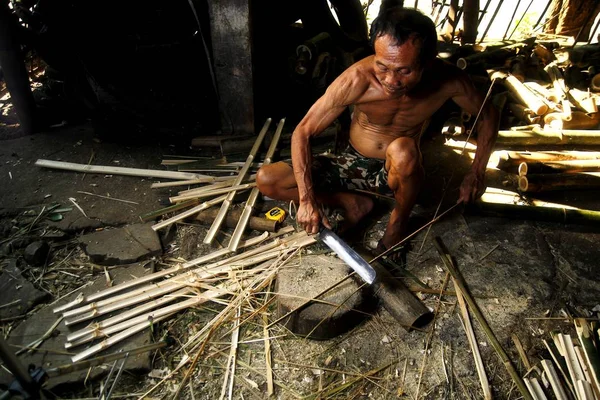 Photo of a bamboo furniture maker cutting bamboo
