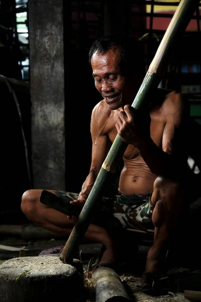 Photo of a bamboo furniture maker cutting bamboo