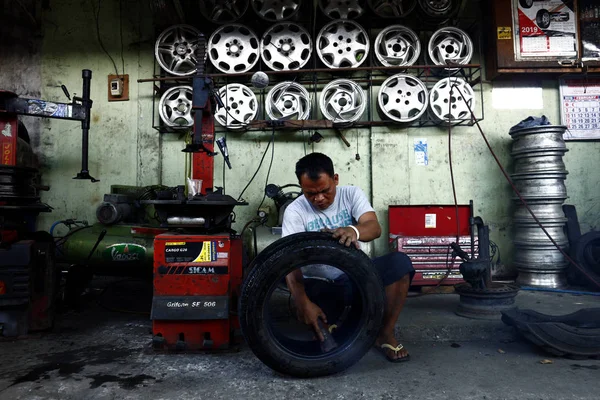 A worker at a tire vulcanizing shop repairs a tire for a customer. — Stock Photo, Image