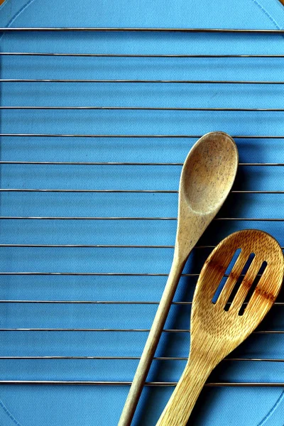 Colheres de cozinha de madeira em um rack de secagem em uma tampa de mesa azul — Fotografia de Stock