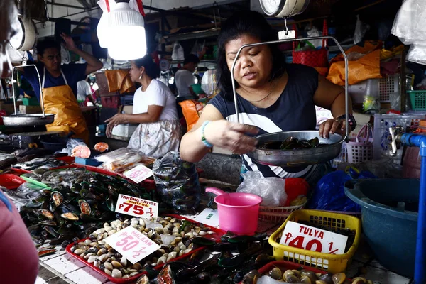 Um vendedor de peixe pesa alimentos com casca para um cliente . — Fotografia de Stock