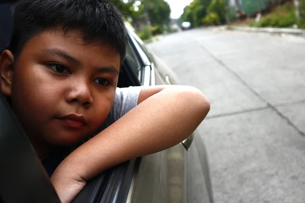 若いアジアの少年が車の窓から外を見る — ストック写真