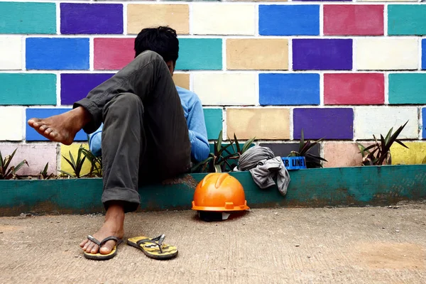 Un obrero de la construcción se quita el casco y descansa en una acera —  Fotos de Stock
