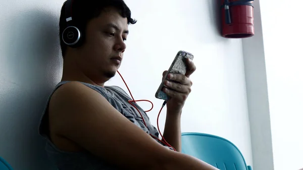 An adult Filipino man uses a smartphone while sitting on a bench — Stock Photo, Image