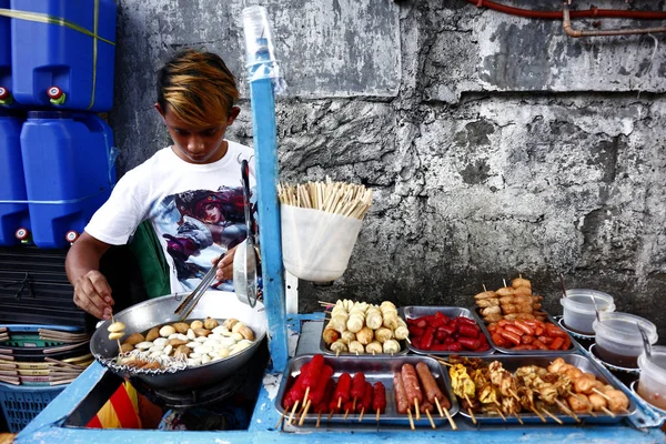 Продавец уличной еды жарит рыбные шарики в тележке с едой. — стоковое фото