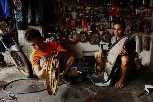 A worker at a motorcycle repair shop fix the spokes of a motorbike���s wheel. — Stock Photo, Image