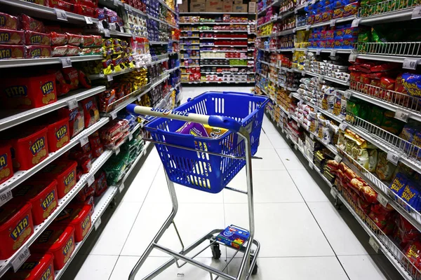 Un carrito de la compra del jalá del cliente en el medio de un pasillo de una tienda de comestibles . — Foto de Stock